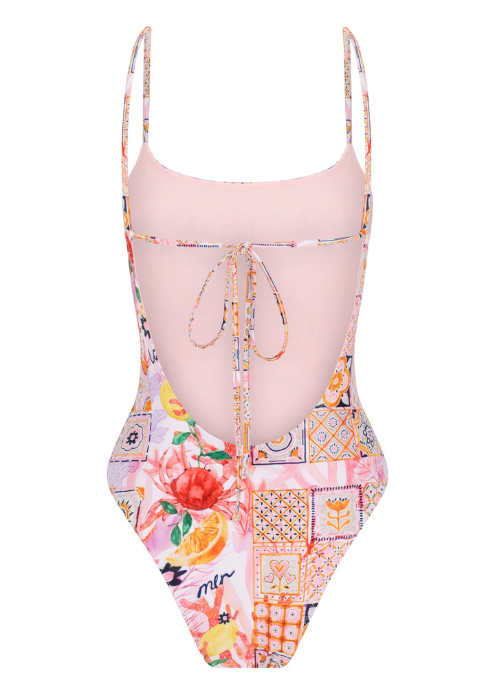 Back view of the colorful La Mer One Piece swimsuit with thin straps, featuring a vibrant patchwork of floral and geometric patterns, including fruits, flowers, tiles, and the word "la mer" on pink background, low cut on the back, a bow-tied thin back strap, cheeky coverage on a white backdrop.